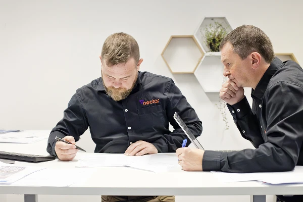Two Nectar team members reviewing documents together at a desk